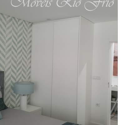 Guarda-roupa embutido branco num quarto com papel de parede azul claro geométrico