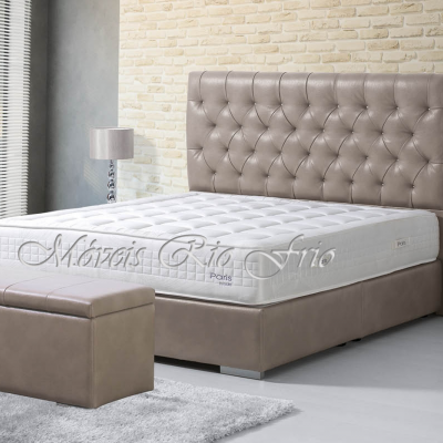 Cama de casal estofada bege com colchão branco e logo, baú e mesa de cabeceira branca em quarto moderno