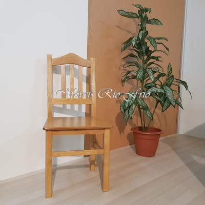 Cadeira de madeira clara ao lado de planta verde em vaso.