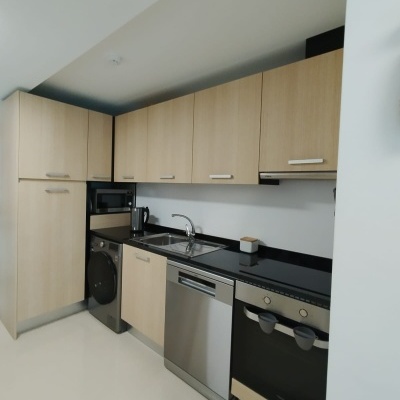 Cozinha moderna com armários de madeira clara e eletrodomésticos em inox e preto