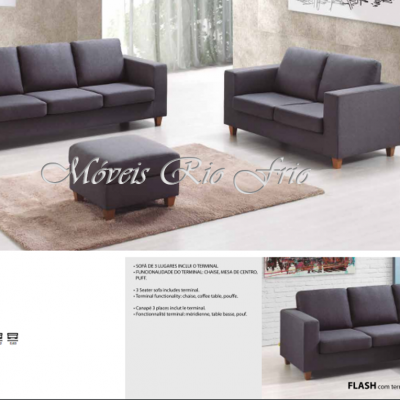 Conjunto de sala com dois sofás cinza escuro, mesa de centro estofada e tapete bege