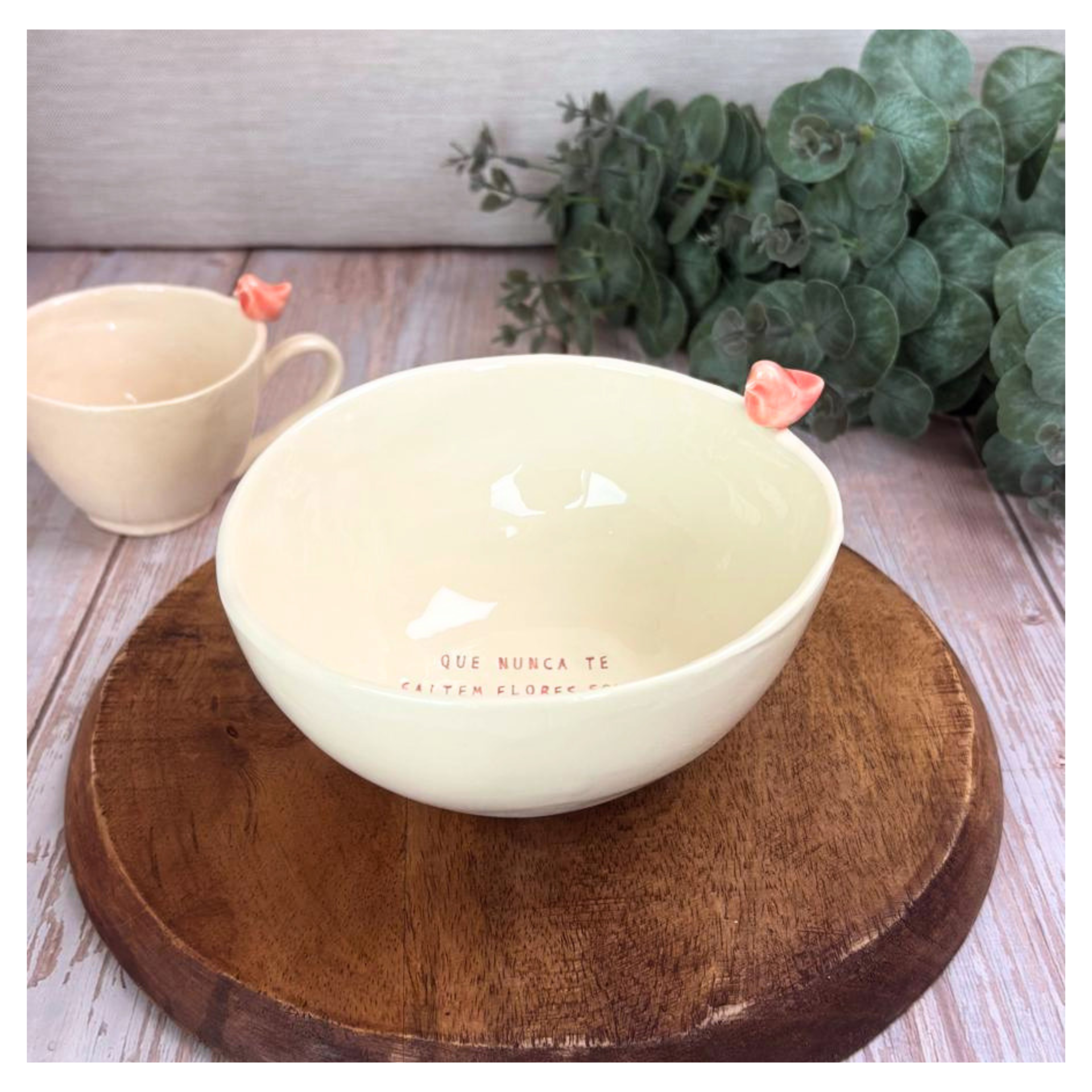 Taça Grande Personalizada Conjunto cerâmico creme com pássaro coral no bordo e texto dentro do bowl sobre base de madeira.