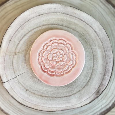 Prato cerâmico rosa com relevo floral sobre madeira clara