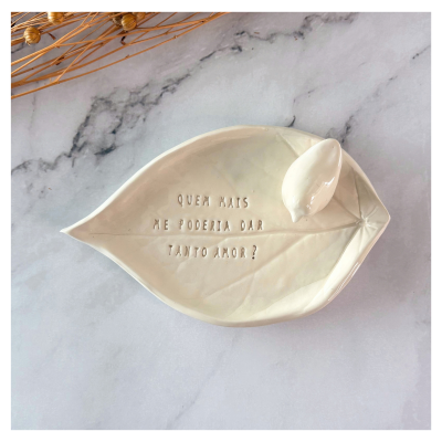 Prato decorativo branco em forma de folha com uma frase gravada e um pequeno pássaro em cerâmica