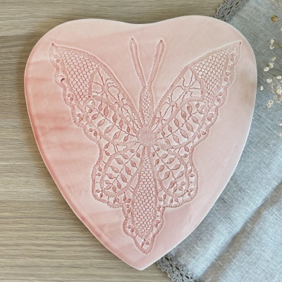 Caixa coração rosa com bordado de borboleta sobre madeira clara e tecido cinza bordado