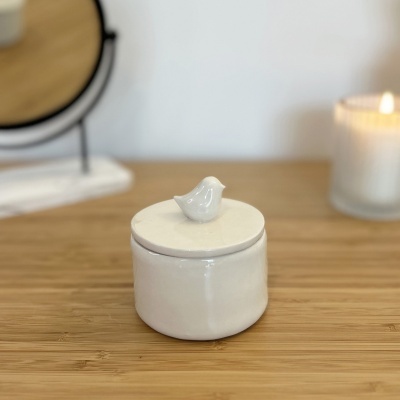 Pote cerâmico branco com tampa e pássaro decorativo em madeira clara