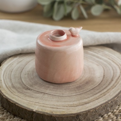 Recipiente de cerâmica rosa com pássaro sobre base de madeira