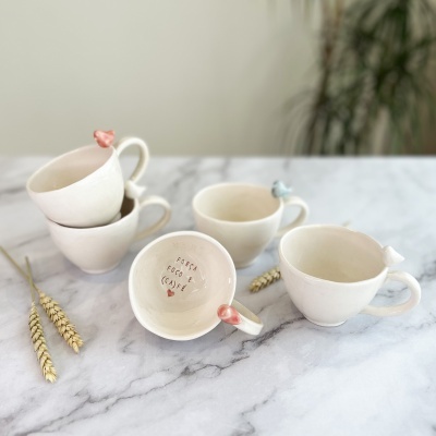 Cinco chávenas de porcelana bege com corações nas pegas sobre mármore branco