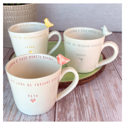 Três canecas de cerâmica creme com pássaros decorativos em cores pastel e texto personalizado em português.