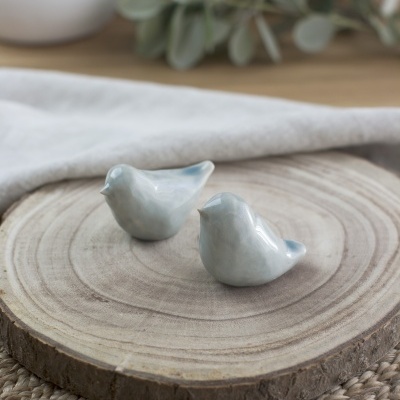 Esculturas decorativas de pássaros cinza claro em base de madeira redonda