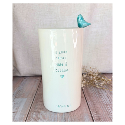 Caneca branca com pássaro azul no bordo e frase gravada em relevo azul