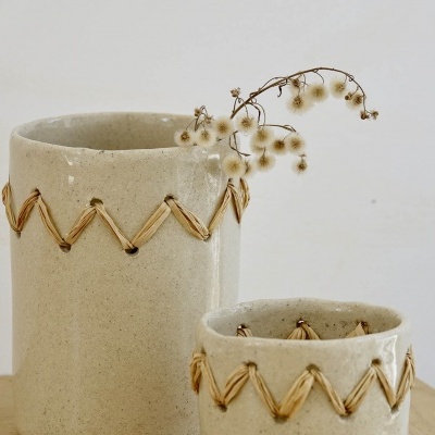 Dois vasos de cerâmica bege com padrão em corda sobre superfície de madeira