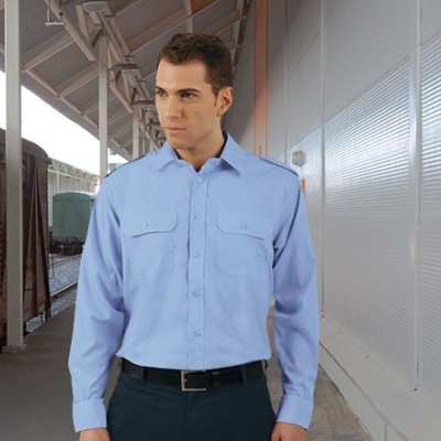 Homem a usar camisa azul clara de manga comprida numa estação ferroviária.
