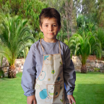 Menino com avental bege estampado com maçãs e flores, em relva com palmeiras ao fundo