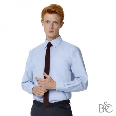 Homem com camisa azul claro, gravata preta e calças escuras sobre fundo branco