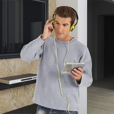 Homem a ouvir música com auscultadores amarelos e leitor de cassetes prateado, em ambiente interior com parede de pedra