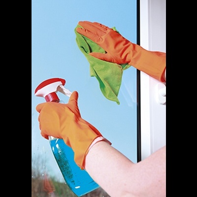 Pessoa a limpar janela com pano verde e spray azul, usando luvas laranja.