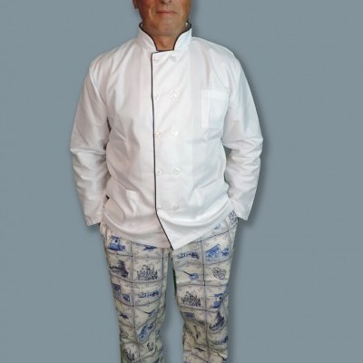 Homem com casaco de chef branco e calças estampadas azuis e brancas