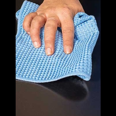 Mão a limpar superfície preta com pano azul texturizado