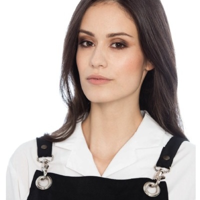 Mulher vestindo camisa branca e vestido preto com alças metálicas prateadas