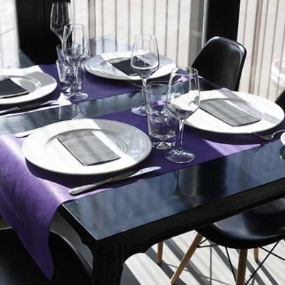 Mesa de jantar preta com caminho de mesa roxo e louça branca