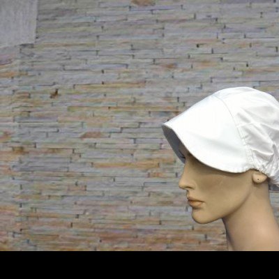 Chapéu branco de tecido em manequim com parede de tijolos ao fundo
