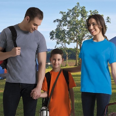 Família com t-shirts coloridas num parque com tenda e árvores ao fundo.