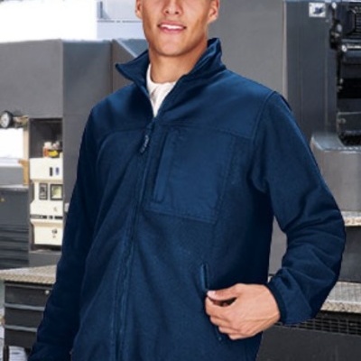 Homem com casaco azul escuro com fecho, em ambiente industrial