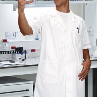 Homem com bata branca segurando béquer em laboratório