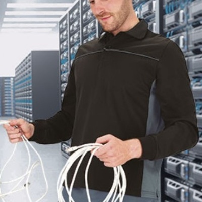 Homem com camisa preta e calças cinzentas segurando cabos brancos em sala de servidores