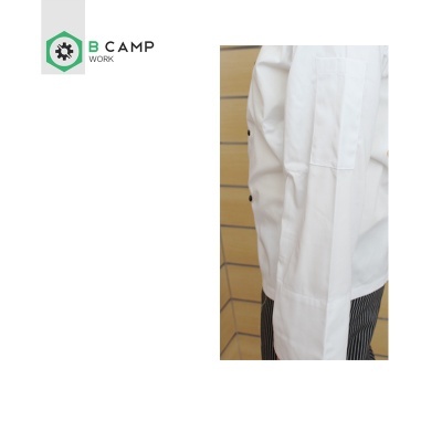 Bata branca de trabalho com logotipo B CAMP WORK e parede de azulejos bege ao fundo
