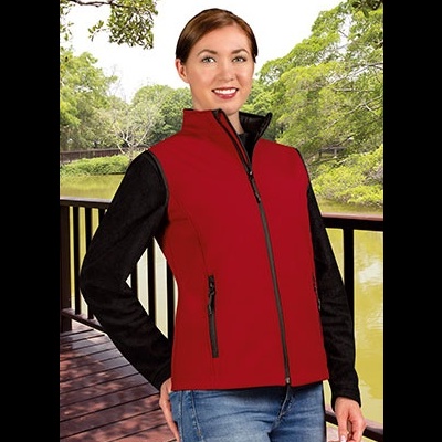 Colete vermelho com fecho preto usado por mulher em ambiente natural ao lado de lago