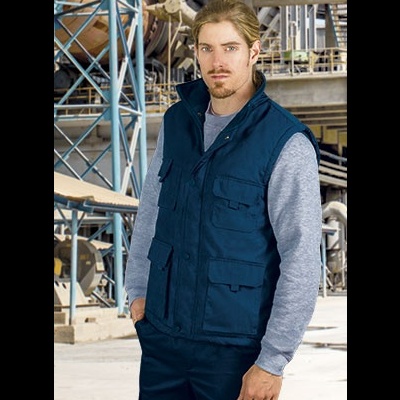 Homem com colete azul e t-shirt cinzenta em ambiente industrial