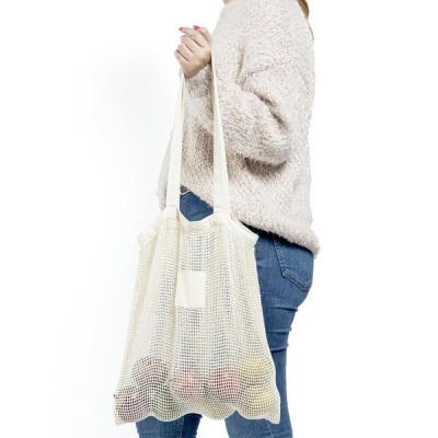 Pessoa segurando saco de rede de algodão cru com alças longas e conteúdo dentro