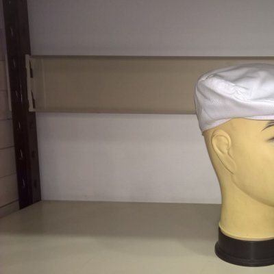 Boné branco tipo boina em manequim numa prateleira