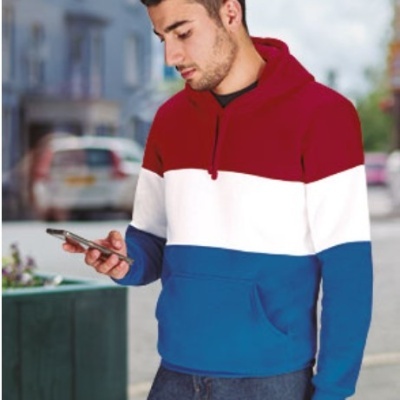 Homem a usar hoodie tricolor vermelho, branco e azul a olhar para telemóvel na rua