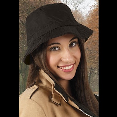 Mulher com chapéu preto estilo pescador e casaco bege ao ar livre com árvores de outono