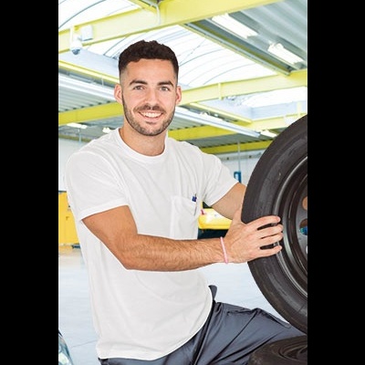 Homem segurando pneu automóvel num ambiente industrial