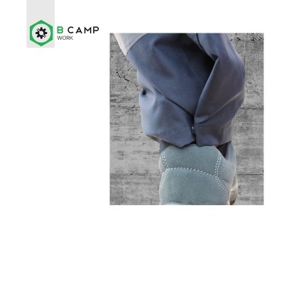 Calça azul e bota cinza com costuras em fundo de parede cinzenta