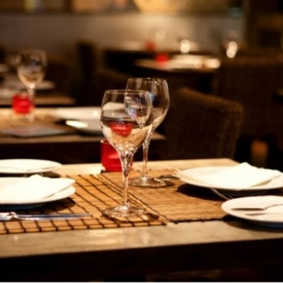 Mesa posta com pratos, copos e guardanapos em restaurante com iluminação quente