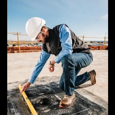 Homem com capacete branco e nível amarelo numa obra ao ar livre