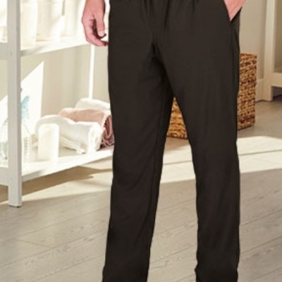 Calças pretas com cordão na cintura num ambiente interior com prateleiras e chão de madeira