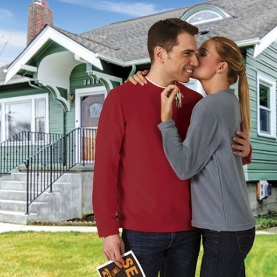 Casal abraçado em frente a casa verde