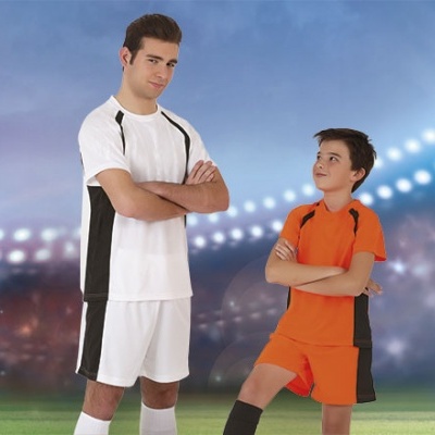 Dois rapazes em equipamento de futebol branco e laranja num campo iluminado