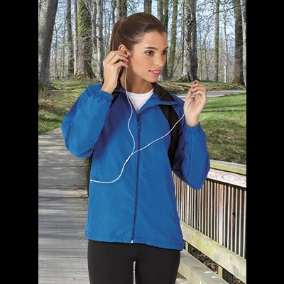 Mulher com casaco azul e auriculares ao ar livre num passadiço de madeira