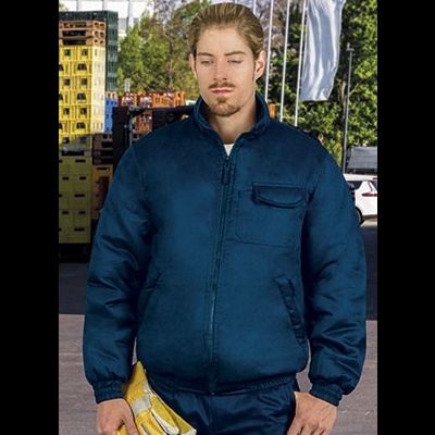 Homem com casaco azul escuro segurando luvas amarelas em ambiente industrial exterior