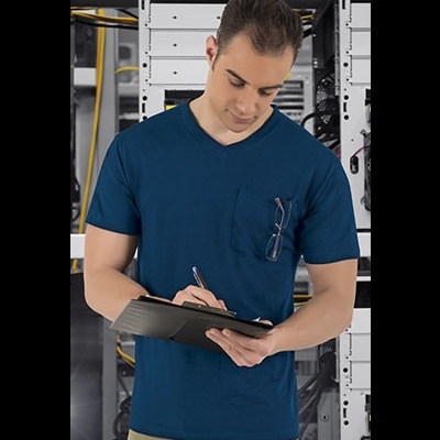 Homem com t-shirt azul com óculos no bolso segurando prancheta em ambiente com servidores