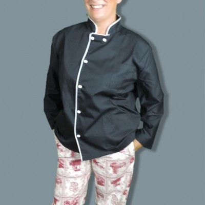 Pessoa com uniforme de cozinheiro preto e calças estampadas brancas e vermelhas, gorro branco com padrão vermelho