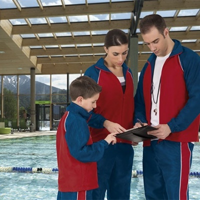 Três pessoas com fatos de treino vermelhos e azuis junto a piscina interior