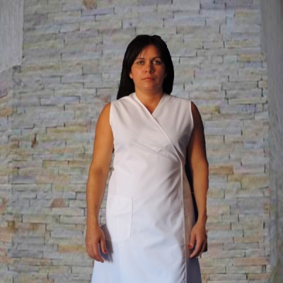 Vestido branco com bolso frontal usado por mulher em fundo de parede de pedra clara